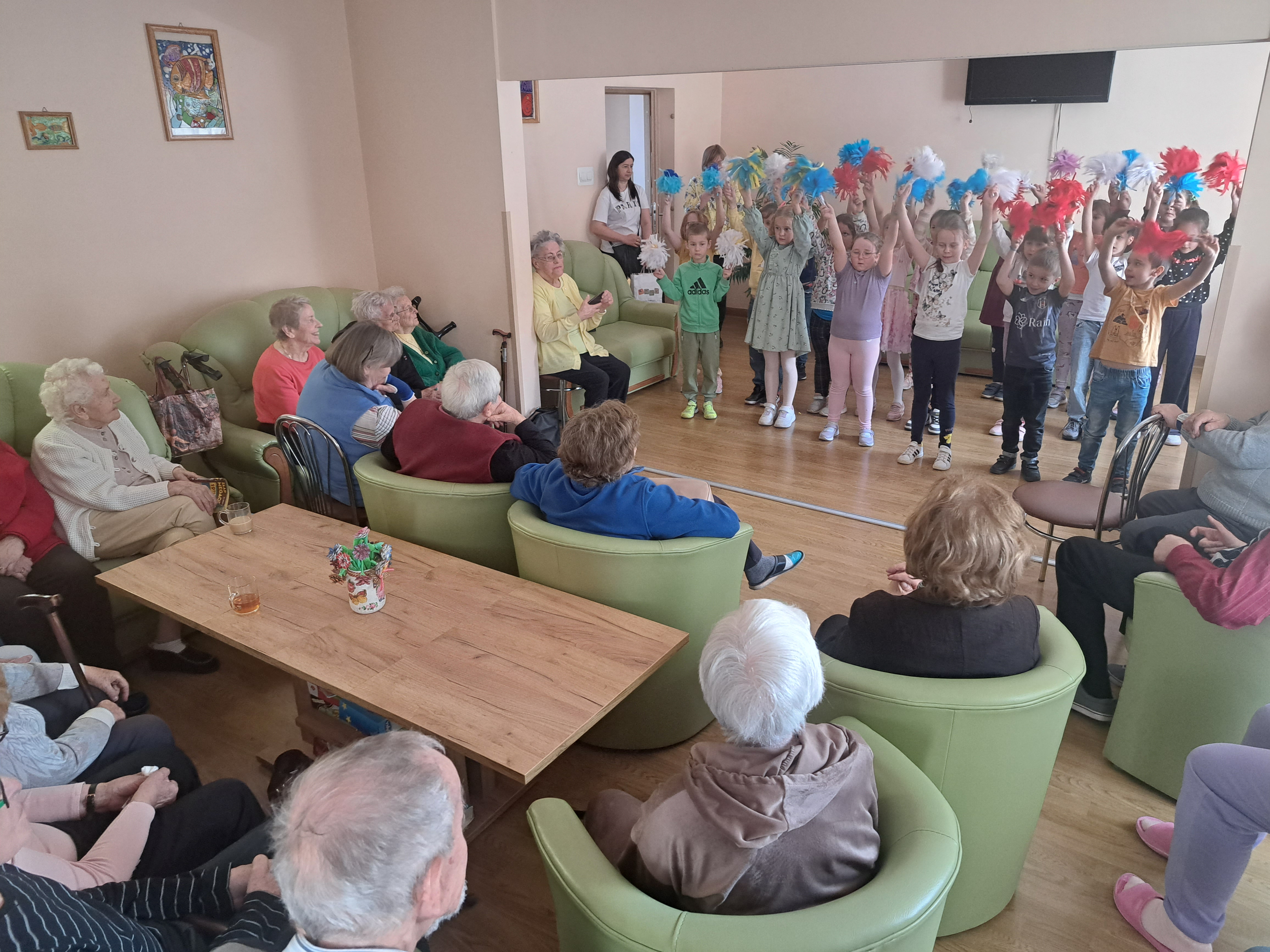 Seniorzy oglądają występ dzieci tańczących z pomponami